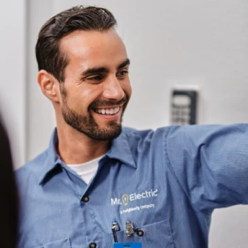 A smiling male Mr. Electric associate explaining a home wiring update to a customer