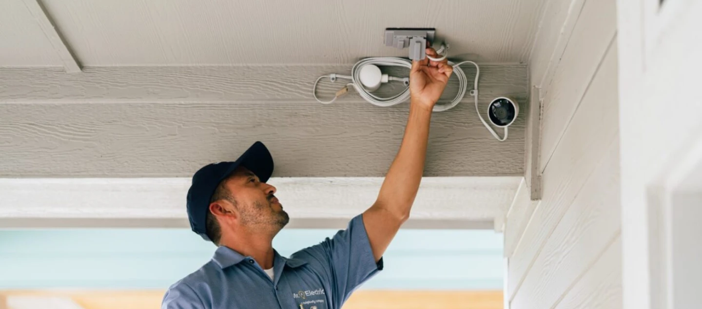 Mr. Electric electrician installing an outdoor security camera.