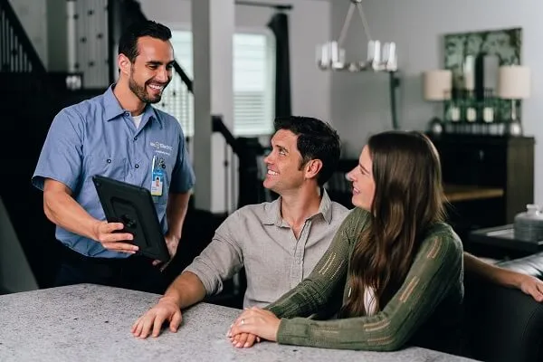 A smiling Mr. Electric electrician shows a tablet to customers.