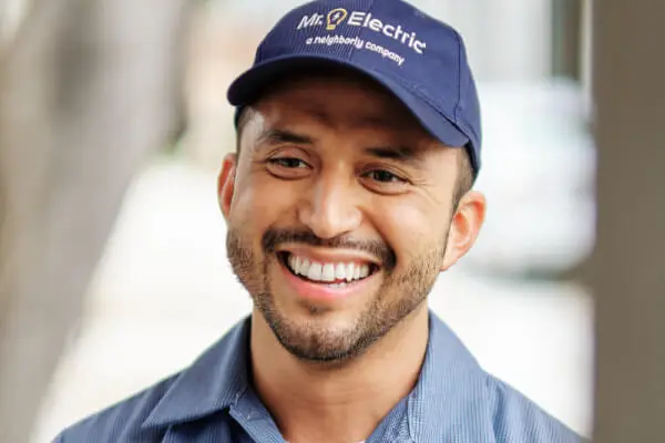 Close up of the head and shoulders of a smiling Mr. Electric service professional wearing a blue Mr. Electric hat. 