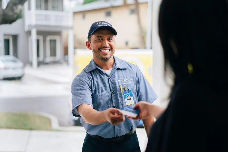 Mr. Electric electrician handing his business card to a customer.