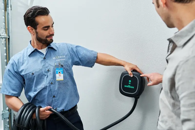MRE electrician showing an EV charger to the customer.
